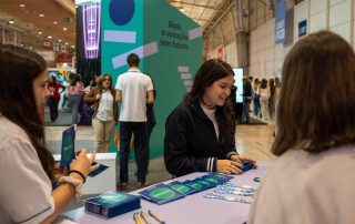 Stand da ESSAlcoitão na Futurália com jovens na bancada dos brindes