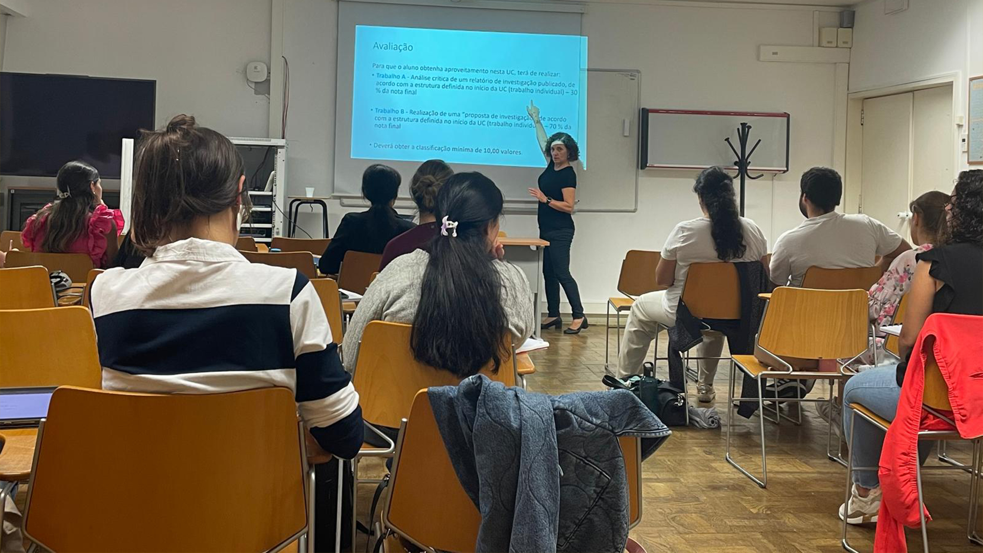 Uma mulher apresenta um tema para um grupo de pessoas atentas em uma sala de conferências.