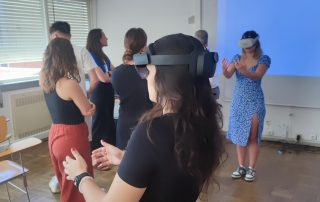 Grupo de pessoas em uma sala de aula, com um headset de realidade virtual